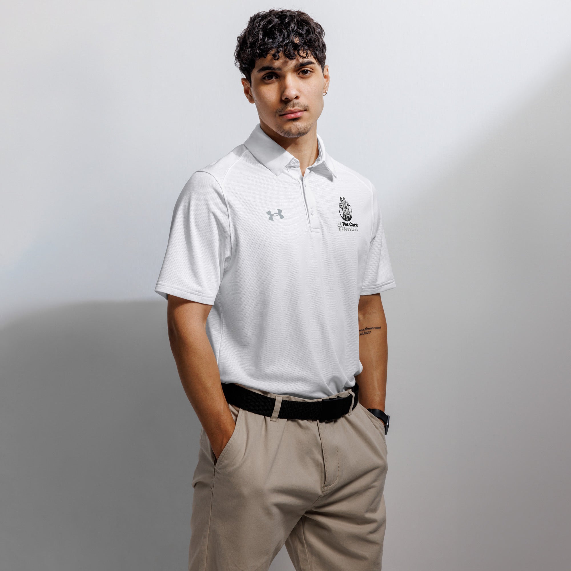Man wearing a white polo shirt with logos on a plain background
