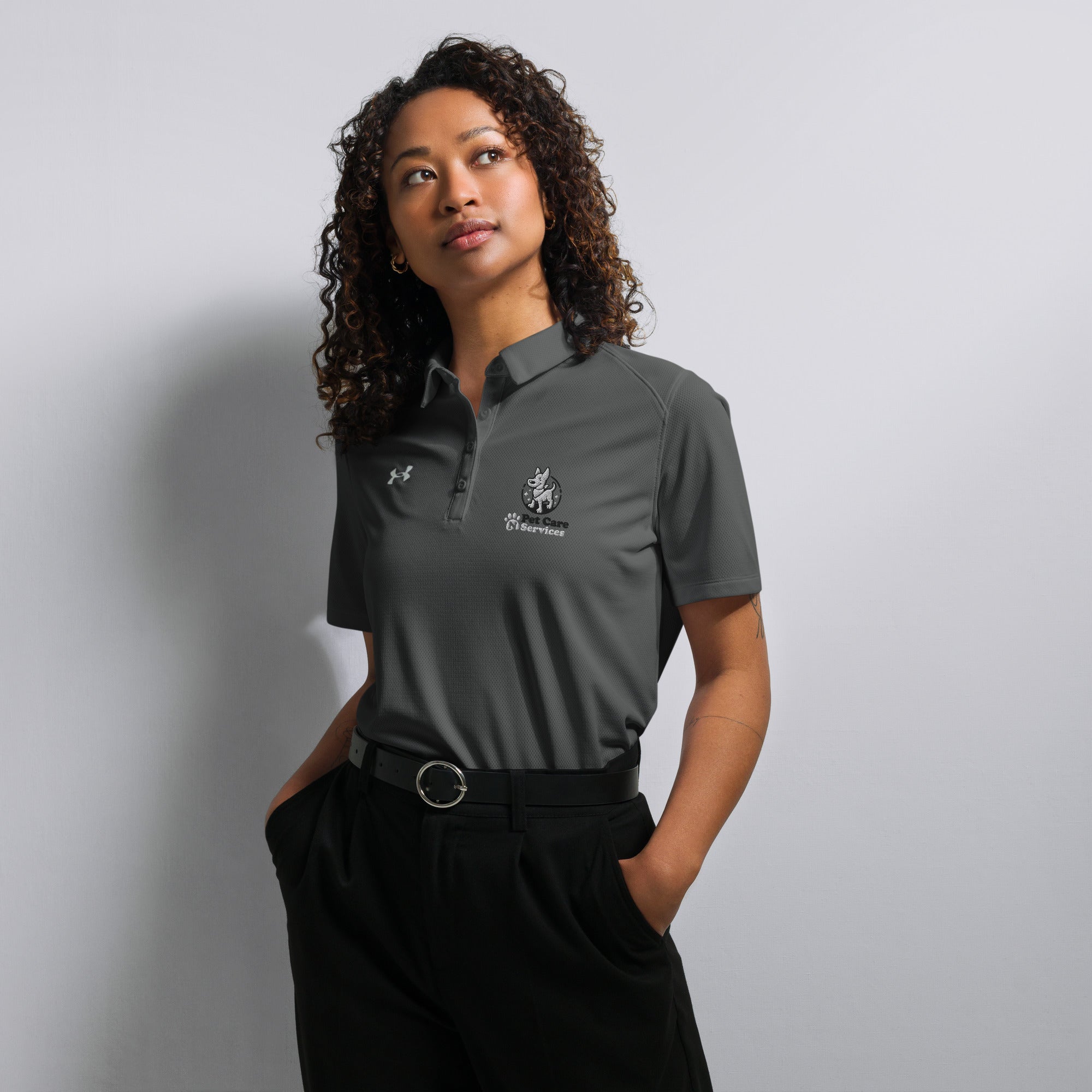 Person wearing a gray Under Armour polo shirt with a logo on a plain background